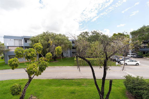 View of buildings with trees and a parking area.
