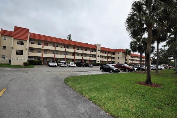 Front view of a three-story apartment building with a parking area in front.