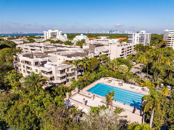 Aerial view of a residential complex with a swimming pool and surrounding greenery.