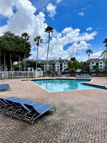 Outdoor swimming pool area with lounge chairs and a fence surrounding it.
