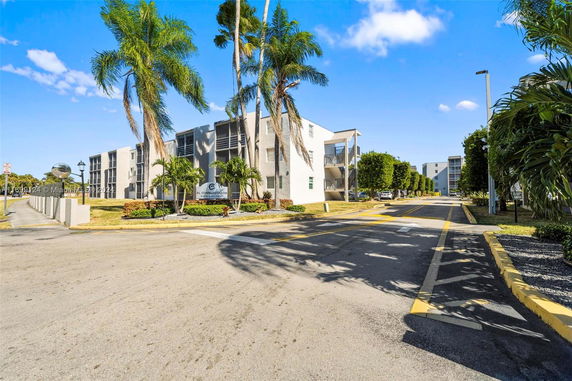 Front view of a modern apartment complex with palm trees.