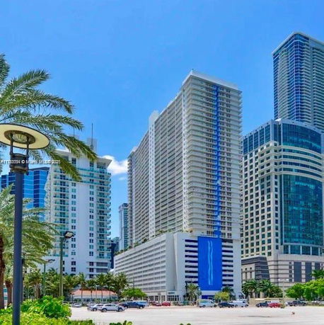 Front view of a high-rise building with a large blue mural and surrounding skyscrapers.