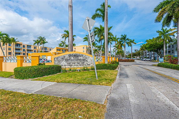 Front view of a multi-story condominium building with palm trees.