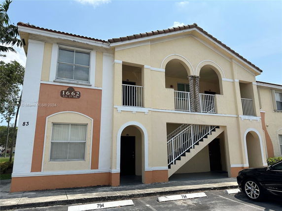 Front view of a two-story building with arched balconies and exterior staircase.
