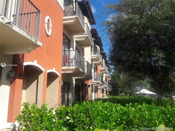 Side view of a multi-story residential building with balconies and orange and beige facade.