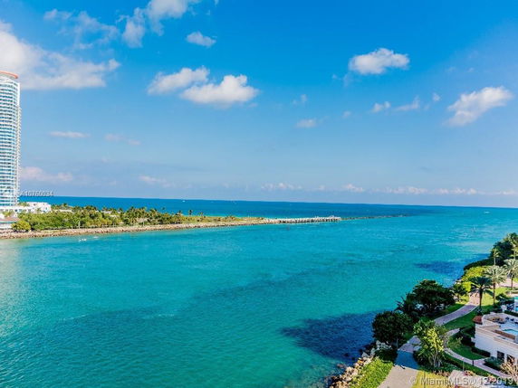 View of a coastal area with a tall building and a shoreline.