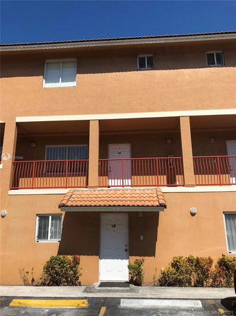 Front view of a multi-story building with an exterior balcony and tile roof.