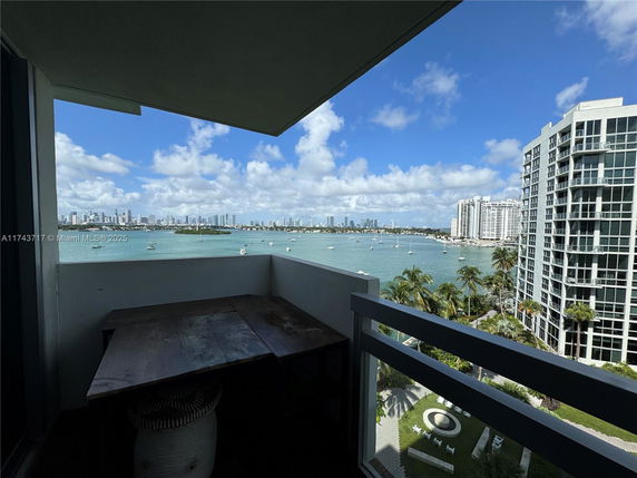 Balcony view overlooking the water with city skyline and adjacent buildings.