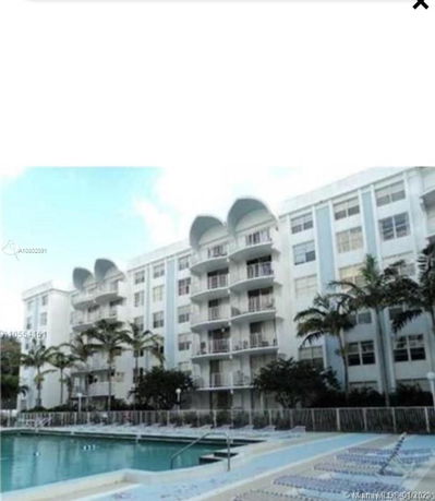 View of a multi-story residential building with balconies and a swimming pool in the foreground.
