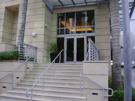 Entrance of a building with glass doors and a staircase leading up to it.