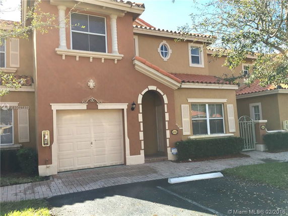 Front view of a two-story house with a single garage and arched entrance.