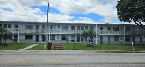Front view of a two-story residential building with a flat roof and a balcony.