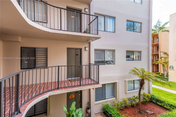 Front view of a multi-story residential building with balconies and greenery.
