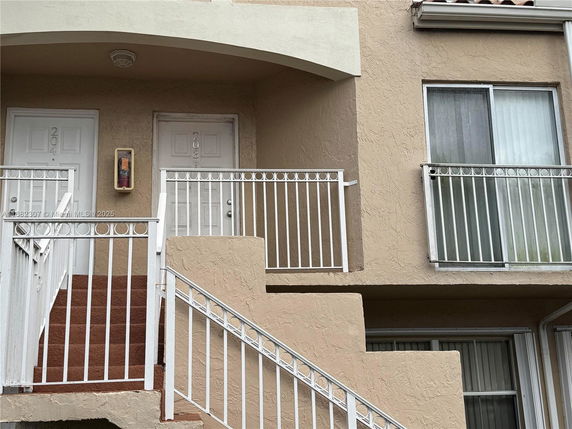View of the staircase leading to two doors with balconies in an apartment building.
