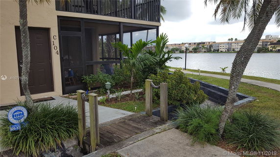 Partial view of a building with a screened porch and lakeside path.