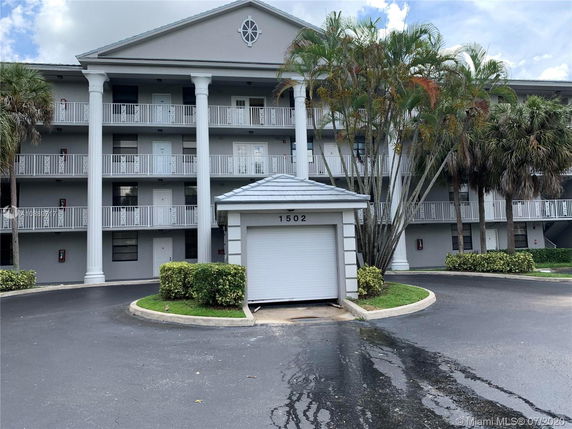 Front view of a multi-story building with prominent columns and a small garage.
