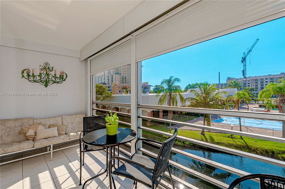 Balcony with outdoor seating overlooking a pool area and city buildings.