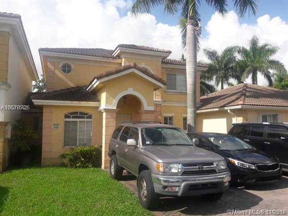 Front view of a two-story house with a tiled roof and an arched entrance.