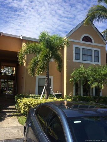 Front view of a two-story building with palm trees and parking area.
