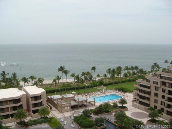 A panoramic view of the ocean with apartment buildings and a swimming pool in the foreground.