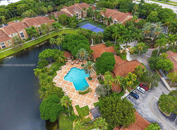 Aerial view of a swimming pool surrounded by trees and buildings.
