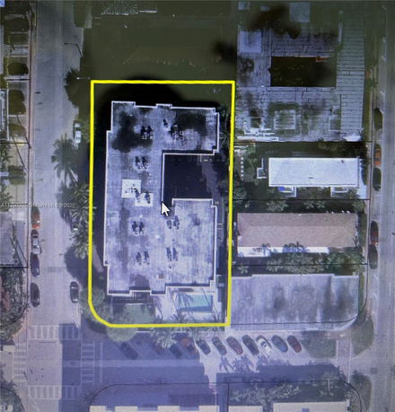 Aerial view highlighting a building with a defined perimeter and visible rooftop features.