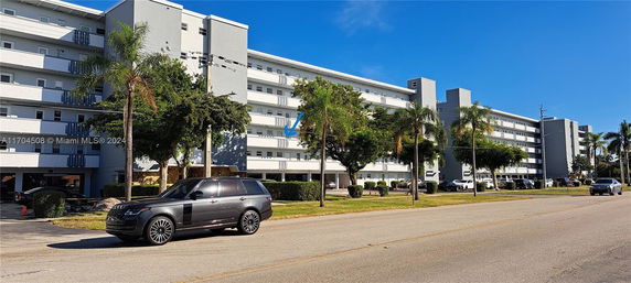 Front view of a multi-story residential building with parking area.