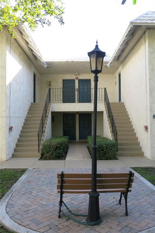 Front view of a building with an outdoor staircase and multiple doors.