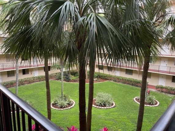 View of a residential courtyard with balconies and palm trees.
