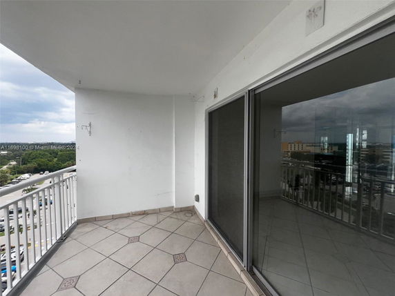 View from a balcony with tiled flooring and sliding glass doors.