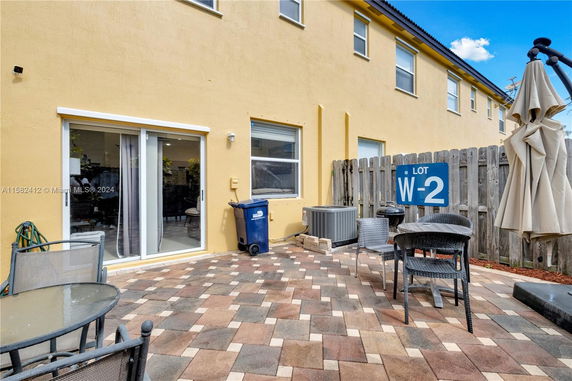 Backyard area of a yellow building with a patio, sliding door, and outdoor seating.