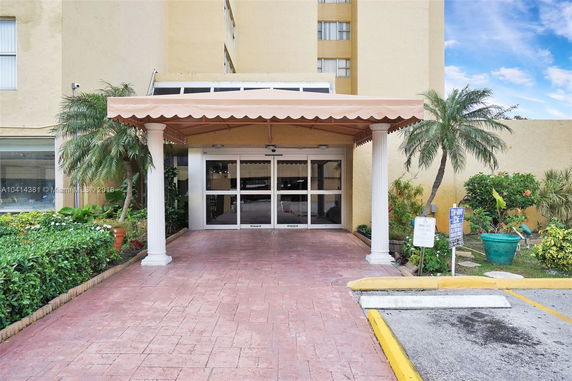Entrance view of a multi-story building with a covered driveway and sliding glass doors.