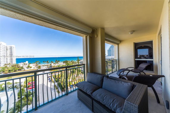 Balcony view overlooking a coastal area with ocean and buildings.