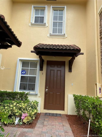 Front view of a two-story house with a brown door and beige exterior.