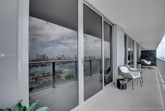 Balcony view with outdoor seating, showing a skyline and water view in the distance.