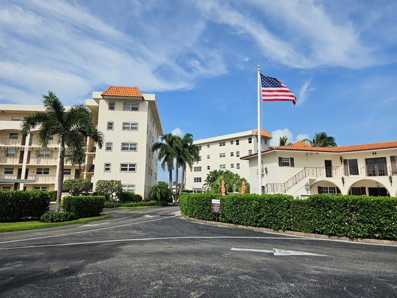 Front view of a multi-story residential building with an American flag and palm trees.
