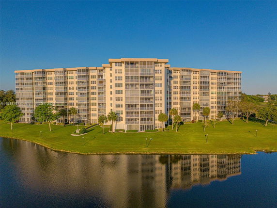 Front view of a multi-story apartment building with large windows and a landscaped lawn.