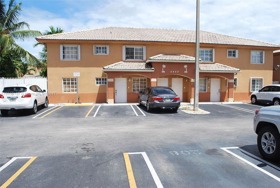 Front view of a two-story building with adjacent parking spaces.