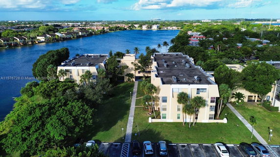 Aerial view of residential buildings near a lake with surrounding greenery.