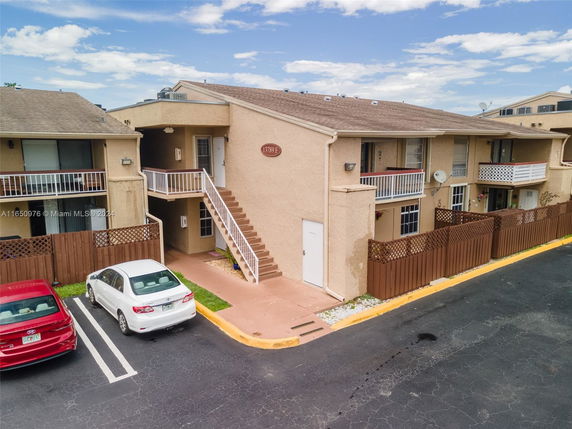 Front view of a two-story building with balconies and an external staircase.