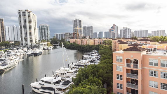 View of waterfront buildings and yachts with high-rise apartments in the background.