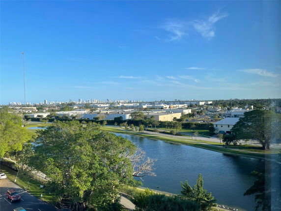 View of a cityscape with buildings and a water body surrounded by trees and greenery.