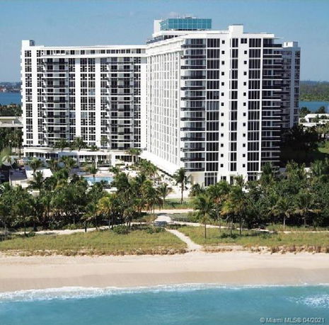 View of a multi-story beachfront condominium building with balconies.