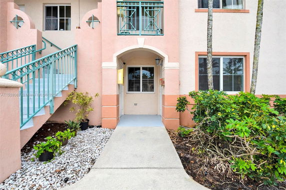 Front view of a multi-story building with exterior stairs and a small garden area.