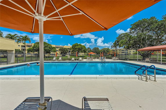 Outdoor swimming pool area with lounge chairs and umbrellas.