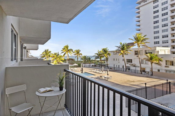 Balcony view of a courtyard with palm trees and adjacent buildings.