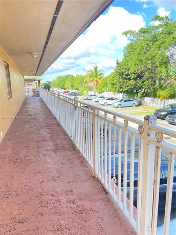Outdoor walkway with a view of parked cars and trees.