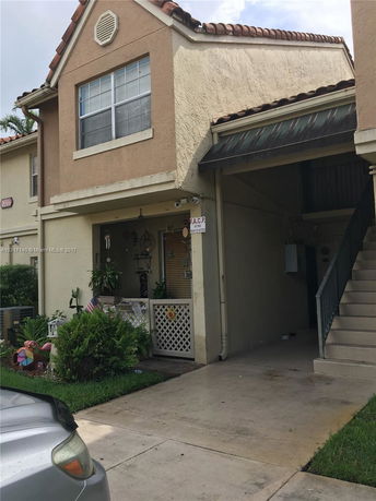 Front view of a two-story house with a covered garage and staircase.