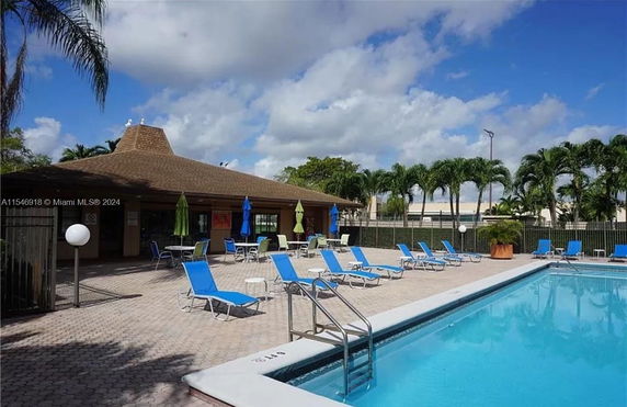 Outdoor swimming pool area with lounge chairs and umbrellas.