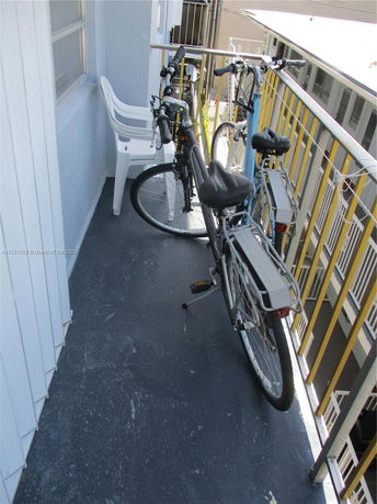Outdoor balcony with bicycles and a plastic chair.
